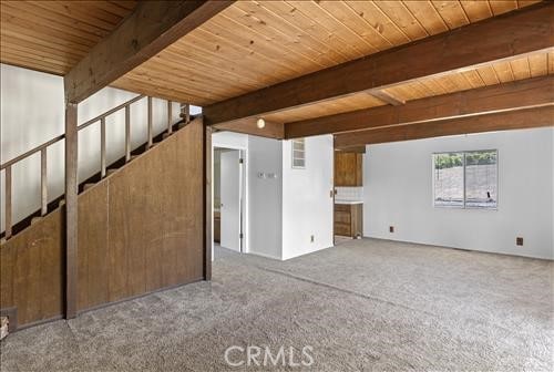 28921 Bear Valley Rd, Tehachapi, CA 93561 - unfurnished room featuring wooden ceiling with exposed beams, carpet flooring, and stairs