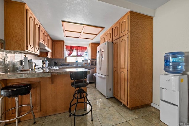 146 Padre Tullio Dr, San Ysidro, CA 92173 - kitchen with freestanding refrigerator, a peninsula, gas range oven, a breakfast bar area, and stainless steel dishwasher