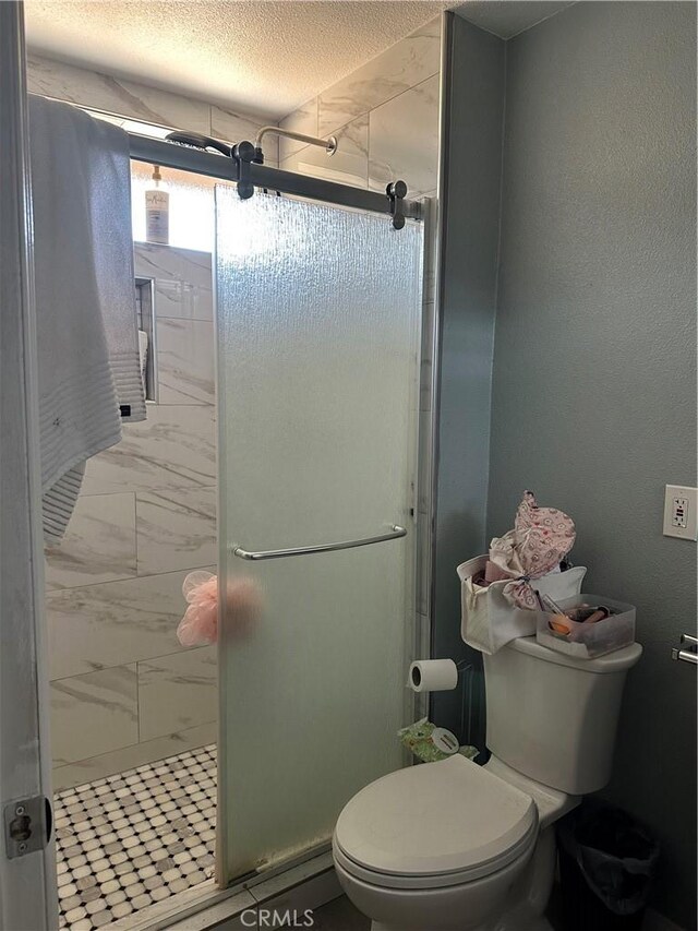 211 N Fillmore Ave, Rialto, CA 92376 - bathroom featuring a stall shower, toilet, marble look tiles, and a textured ceiling