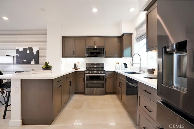 2317 W Broadway, Anaheim, CA 92804 - kitchen featuring appliances with stainless steel finishes, a peninsula, a sink, backsplash, and light countertops