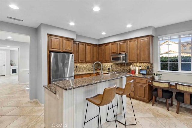 45614 Hawk Ct, Temecula, CA 92592 - kitchen with appliances with stainless steel finishes, decorative backsplash, dark stone countertops, brown cabinetry, and recessed lighting