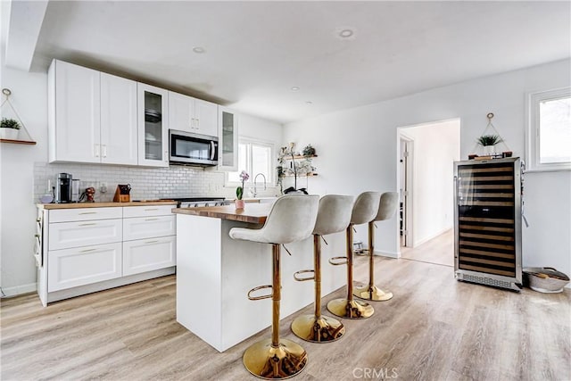 320 E Walnut Ave, El Segundo, CA 90245 - kitchen with stainless steel microwave, beverage cooler, light wood finished floors, and white cabinetry
