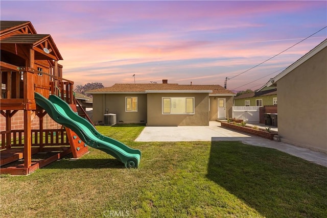 1840 W Southgate Ave, Fullerton, CA 92833 - back of house at dusk featuring central air condition unit, stucco siding, a playground, and a patio