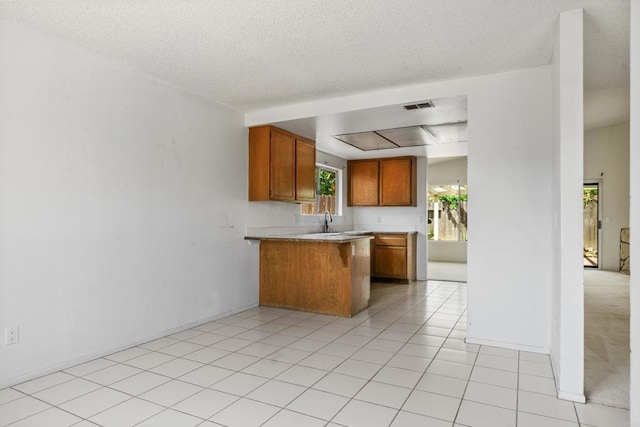 241 Saguaro Pl, Oceanside, CA 92057 - kitchen with a peninsula, brown cabinetry, light countertops, a textured ceiling, and a kitchen breakfast bar