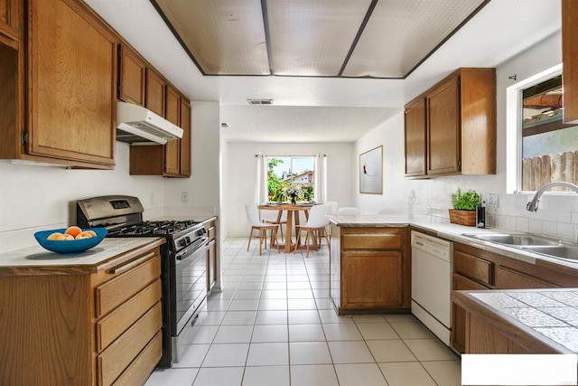 241 Saguaro Pl, Oceanside, CA 92057 - kitchen with stainless steel gas stove, white dishwasher, under cabinet range hood, a sink, and a peninsula