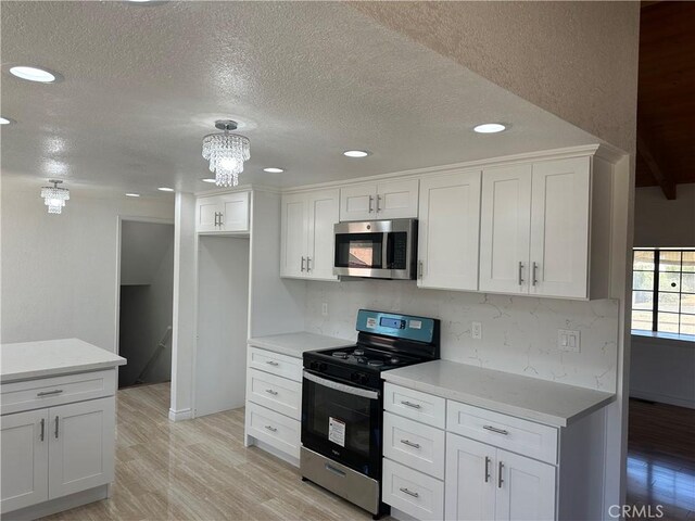 16485 Wintun Rd, Apple Valley, CA 92307 - kitchen with appliances with stainless steel finishes, light wood finished floors, white cabinetry, recessed lighting, and a textured ceiling