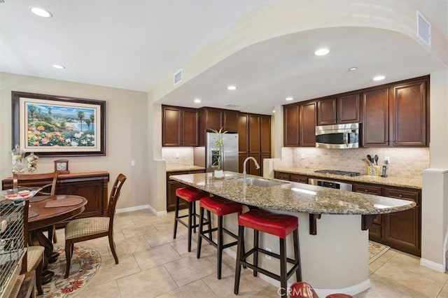 45 Brownstone Way, Aliso Viejo, CA 92656 - kitchen with stainless steel appliances, a sink, a kitchen bar, light stone countertops, and decorative backsplash