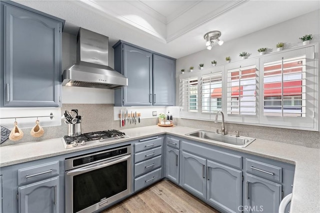 19431 Ranch Ln Unit 101, Huntington Beach, CA 92648 - kitchen with wall chimney exhaust hood, stainless steel appliances, a sink, crown molding, and light wood-style floors