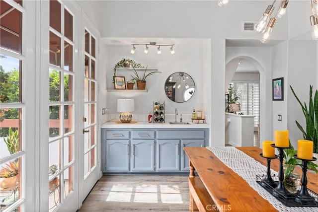 19431 Ranch Ln Unit 101, Huntington Beach, CA 92648 - indoor wet bar featuring arched walkways, light wood-style floors, and french doors