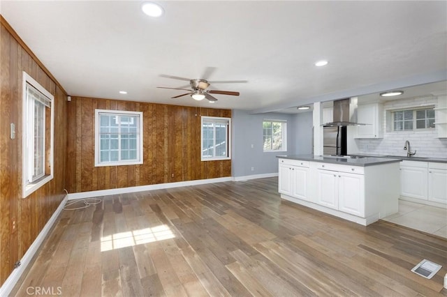799 Fern Dr, Crestline, CA 92325 - kitchen with wall chimney exhaust hood, dark countertops, ceiling fan, baseboards, and light wood finished floors