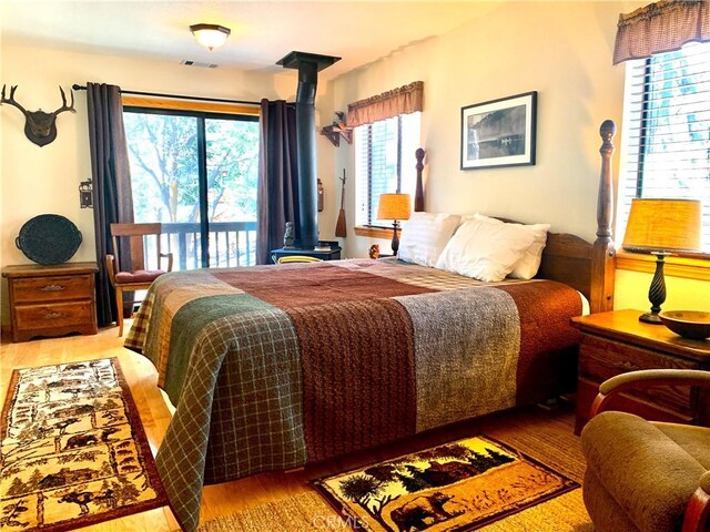 762 Esquimoux Dr, Green Valley Lake, CA 92341 - bedroom with a wood stove, wood finished floors, and access to outside