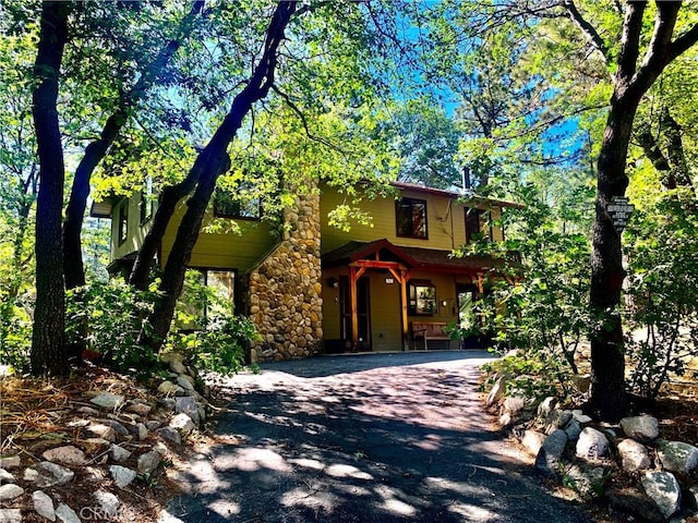 762 Esquimoux Dr, Green Valley Lake, CA 92341 - view of property hidden behind natural elements with asphalt driveway, covered porch, and stone siding