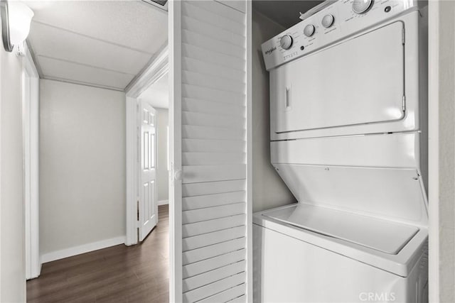 26762 Claudette St Unit 417, Canyon Country, CA 91351 - washroom with stacked washer and clothes dryer, dark wood-type flooring, and baseboards