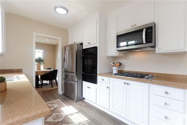1023 W 186th St, Gardena, CA 90248 - kitchen featuring appliances with stainless steel finishes, a warming drawer, light wood-style flooring, white cabinets, and light countertops