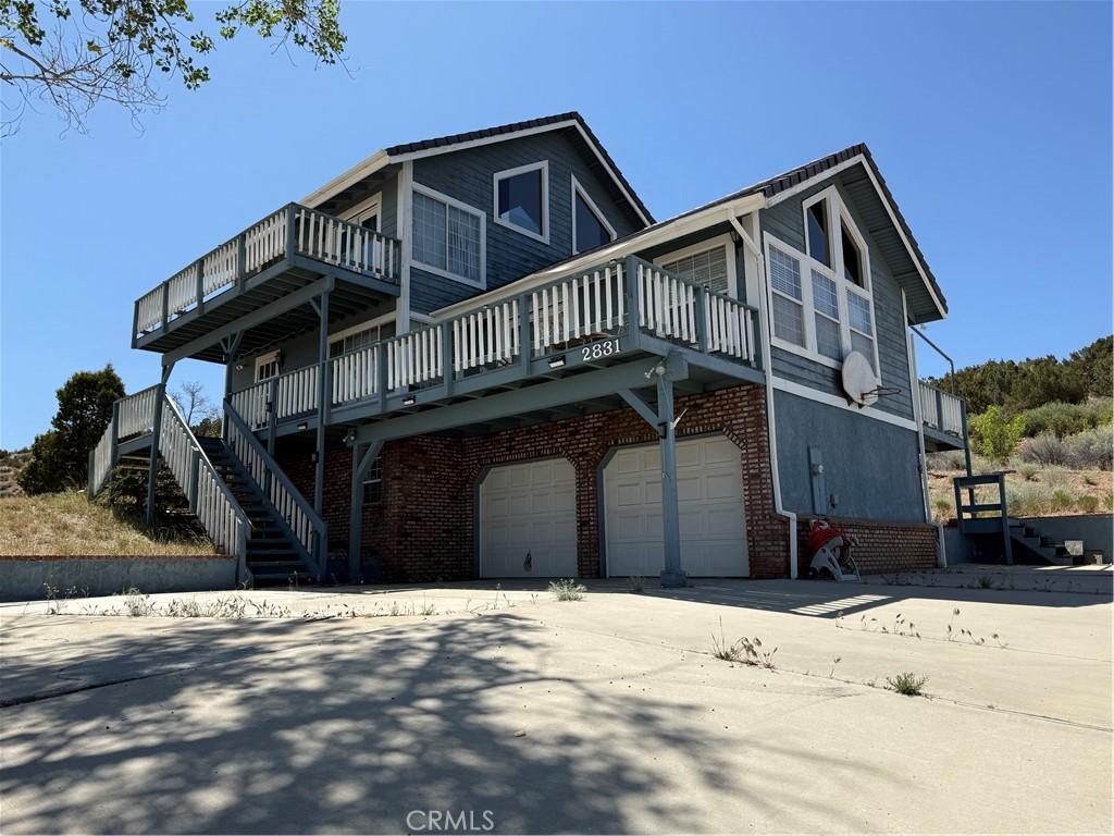 2831 Cygnet Rd, Pinon Hills, CA 92372 - view of side of property featuring brick siding, an attached garage, and stairs