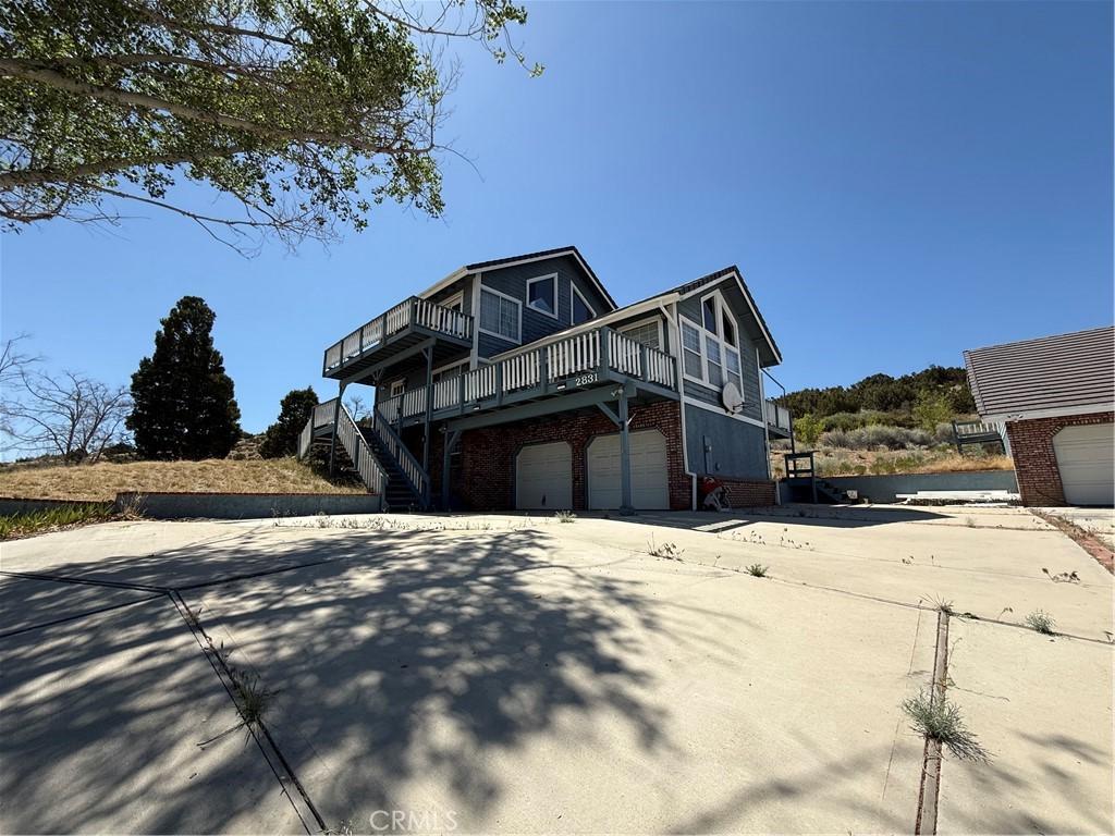 2831 Cygnet Rd, Pinon Hills, CA 92372 - view of side of home featuring brick siding, an attached garage, driveway, a deck, and stairway