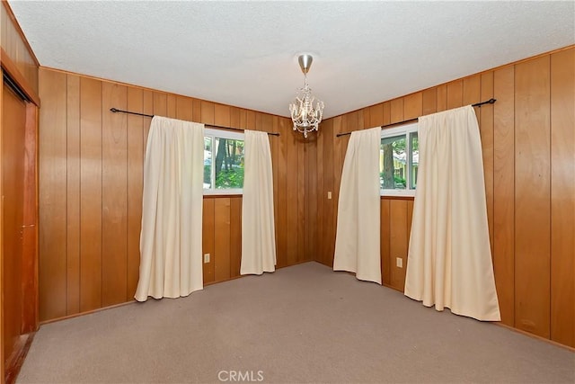 24141 Zell Ct, Crestline, CA 92325 - empty room featuring plenty of natural light, a chandelier, carpet floors, wooden walls, and a textured ceiling