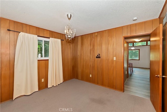 24141 Zell Ct, Crestline, CA 92325 - carpeted empty room featuring plenty of natural light, a chandelier, wood walls, a smoke detector, and a textured ceiling