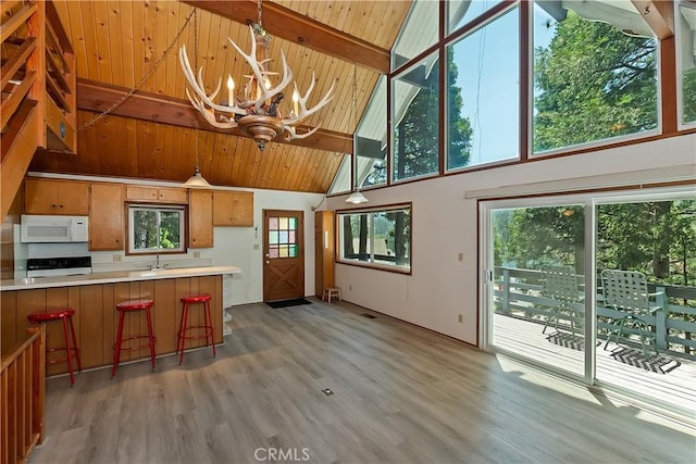 24141 Zell Ct, Crestline, CA 92325 - kitchen featuring white microwave, high vaulted ceiling, a sink, range, and a chandelier