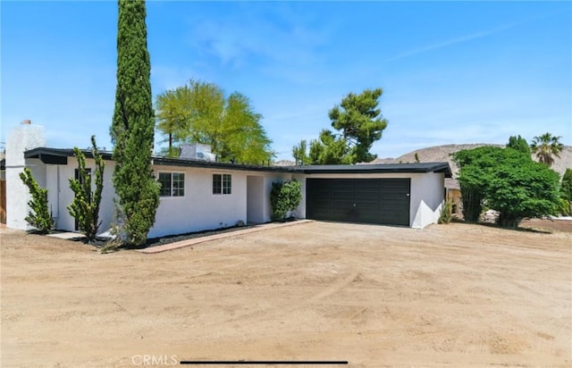 7686 Deer Trl, Yucca Valley, CA 92284 - view of front of home with an attached garage, driveway, and stucco siding