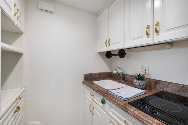 24055 Paseo Del Lago Unit 1206, Laguna Woods, CA 92637 - kitchen with stovetop with downdraft, a sink, white cabinetry, and dark countertops