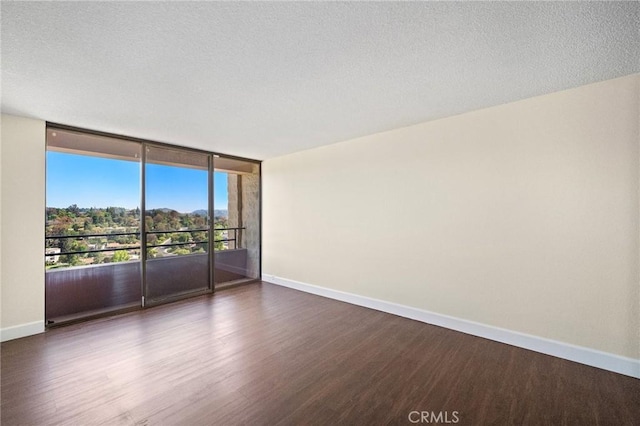 24055 Paseo Del Lago Unit 1206, Laguna Woods, CA 92637 - unfurnished room with baseboards, dark wood-style flooring, a wall of windows, and a textured ceiling