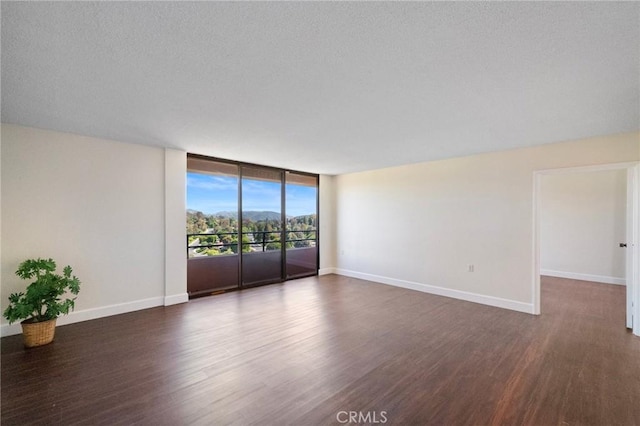 24055 Paseo Del Lago Unit 1206, Laguna Woods, CA 92637 - empty room featuring wood finished floors, baseboards, a wall of windows, and a textured ceiling