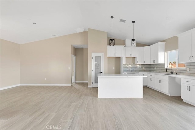 6693 Banyan Ave, Hesperia, CA 92345 - kitchen with a kitchen island, a sink, lofted ceiling, decorative backsplash, and baseboards