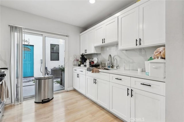 2806 Cudahy St, Huntington Park, CA 90255 - kitchen with light countertops, white cabinetry, a sink, light wood finished floors, and healthy amount of natural light