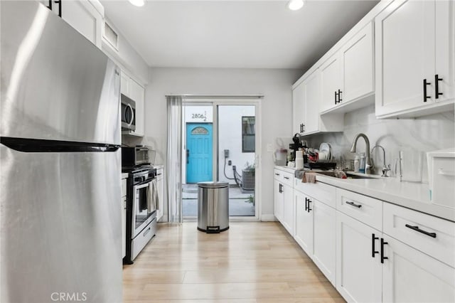2806 Cudahy St, Huntington Park, CA 90255 - kitchen featuring appliances with stainless steel finishes, recessed lighting, white cabinetry, light wood-type flooring, and light countertops