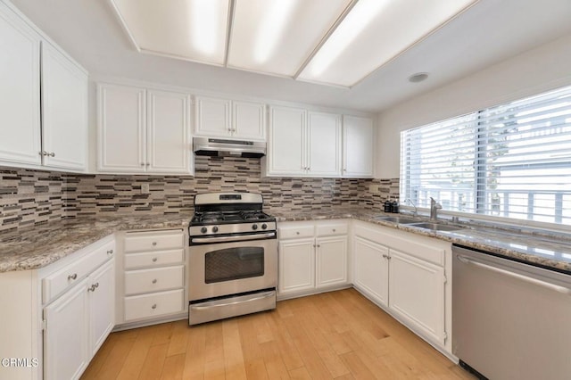 1029 Gilbert Ln, Ventura, CA 93003 - kitchen with stainless steel appliances, exhaust hood, light wood-type flooring, white cabinets, and tasteful backsplash
