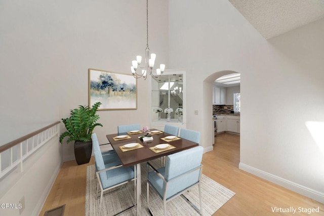 1029 Gilbert Ln, Ventura, CA 93003 - dining space with arched walkways, light wood finished floors, high vaulted ceiling, and a chandelier