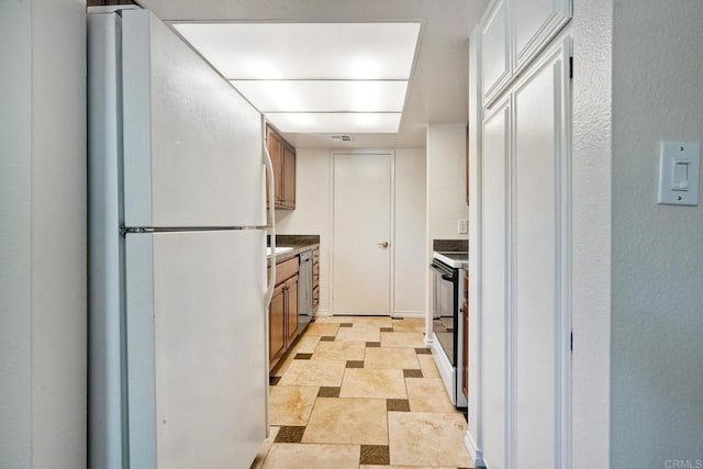 2564 Navarra Dr Unit 115, Carlsbad, CA 92009 - kitchen featuring freestanding refrigerator, dishwasher, range with electric cooktop, stone finish floors, and dark countertops