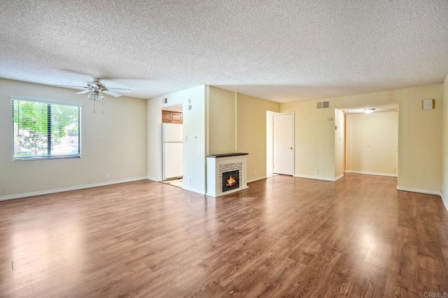 2564 Navarra Dr Unit 115, Carlsbad, CA 92009 - unfurnished living room featuring a textured ceiling, wood finished floors, a ceiling fan, a brick fireplace, and baseboards