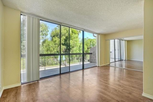 2564 Navarra Dr Unit 115, Carlsbad, CA 92009 - empty room with expansive windows, a textured ceiling, wood finished floors, and baseboards