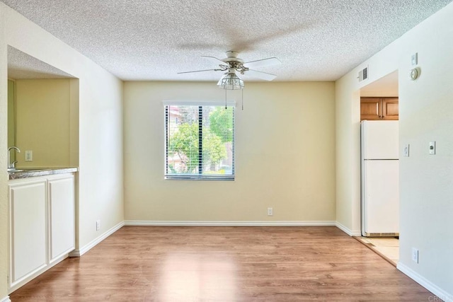2564 Navarra Dr Unit 115, Carlsbad, CA 92009 - unfurnished dining area featuring a ceiling fan, light wood-style floors, and a textured ceiling