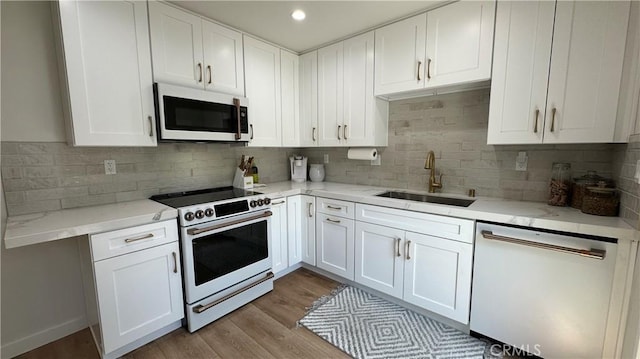 11467 Tampa Ave Unit 154, Porter Ranch, CA 91326 - kitchen with white appliances, a sink, white cabinets, backsplash, and light stone countertops