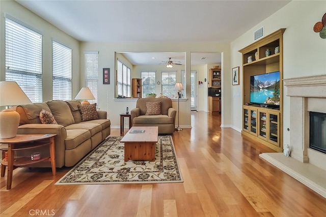 3607 Cascara Ct, Simi Valley, CA 93065 - living room featuring light wood-style flooring, ceiling fan, a glass covered fireplace, and baseboards