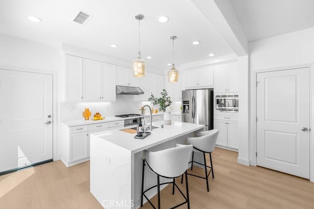 61 Jade Flower, Irvine, CA 92620 - kitchen featuring stainless steel appliances, under cabinet range hood, a kitchen breakfast bar, white cabinets, and recessed lighting