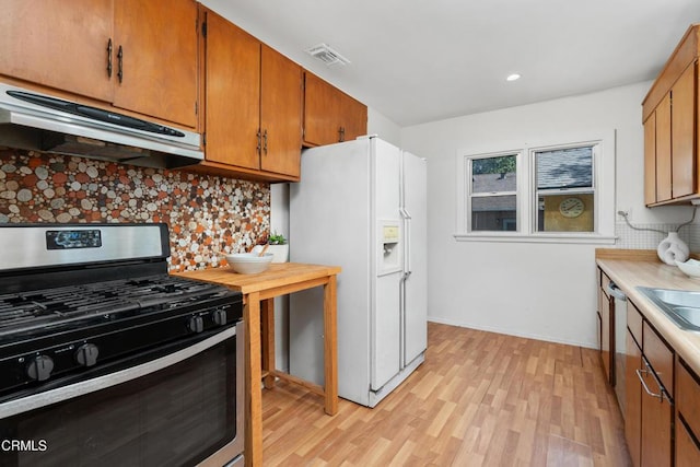 1675 N El Molino Ave, Pasadena, CA 91104 - kitchen with appliances with stainless steel finishes, under cabinet range hood, tasteful backsplash, light wood-style flooring, and light countertops