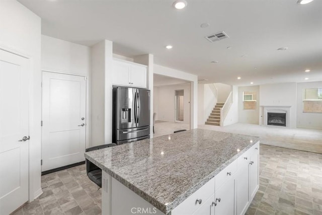 4852 S Jordan Ave, Ontario, CA 91762 - kitchen featuring stainless steel fridge, white cabinetry, light stone counters, a kitchen island, and a fireplace