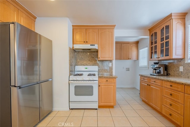 10404 Jardine Ave, Sunland, CA 91040 - kitchen with freestanding refrigerator, white gas range oven, under cabinet range hood, glass insert cabinets, and light stone countertops