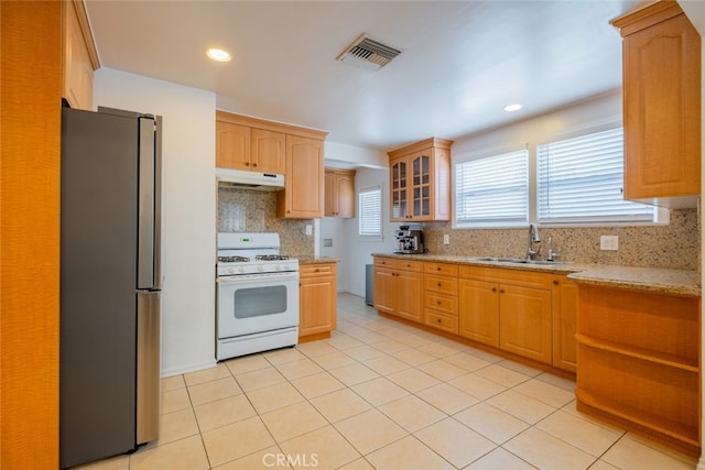 10404 Jardine Ave, Sunland, CA 91040 - kitchen featuring white range with gas stovetop, freestanding refrigerator, under cabinet range hood, a sink, and tasteful backsplash