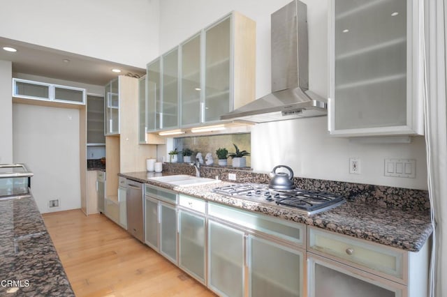 1196 Montecito Dr, Los Angeles, CA 90031 - kitchen featuring wall chimney range hood, appliances with stainless steel finishes, light wood-style flooring, a sink, and dark stone counters