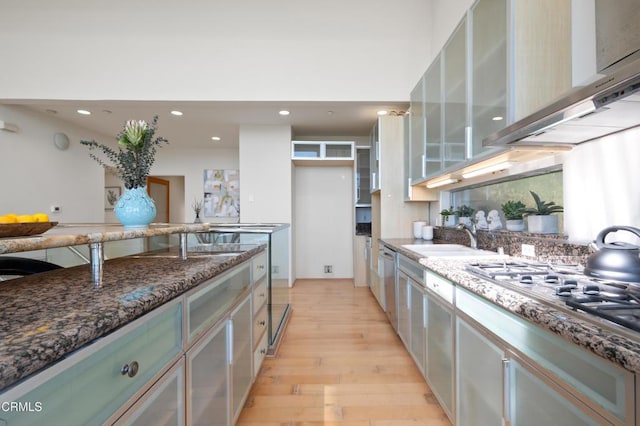 1196 Montecito Dr, Los Angeles, CA 90031 - kitchen featuring a sink, wall chimney range hood, light wood-type flooring, stainless steel gas cooktop, and dark stone countertops