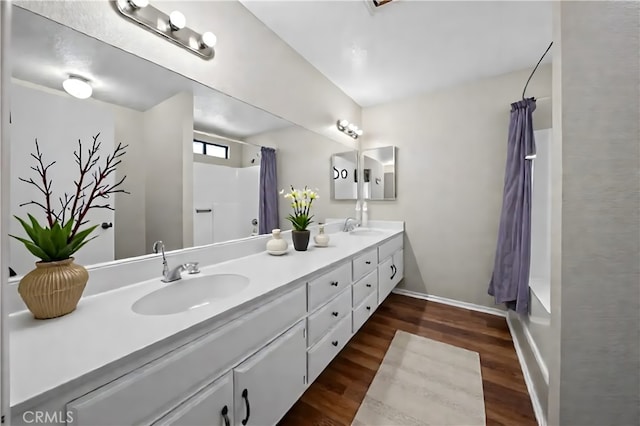 43007 Pearlwood Dr, Lancaster, CA 93536 - bathroom with double vanity, wood finished floors, shower / bathtub combination with curtain, and baseboards