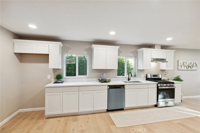 325 N 3rd Ave, Oakdale, CA 95361 - kitchen with appliances with stainless steel finishes, under cabinet range hood, a sink, white cabinets, and light wood finished floors