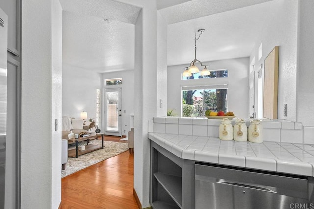 7254 Shoreline Dr Unit 131, San Diego, CA 92122 - kitchen featuring stainless steel dishwasher, tile counters, wood finished floors, plenty of natural light, and a textured ceiling