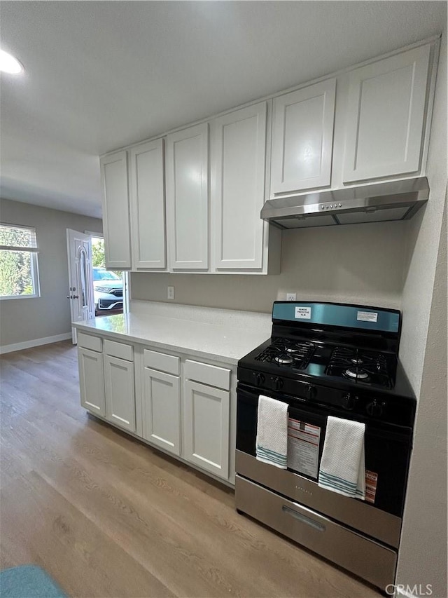15475 Shadow Mountain Ln, Lake Elsinore, CA 92530 - kitchen featuring range with gas stovetop, under cabinet range hood, light wood finished floors, white cabinetry, and light countertops