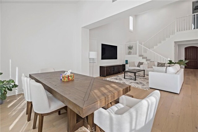 113 Imagination Trl, Irvine, CA 92620 - dining room featuring a high ceiling, stairway, light wood-type flooring, and baseboards